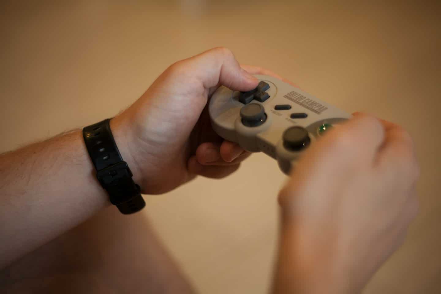 Mani che tengono un controller gamepad retrò grigio.