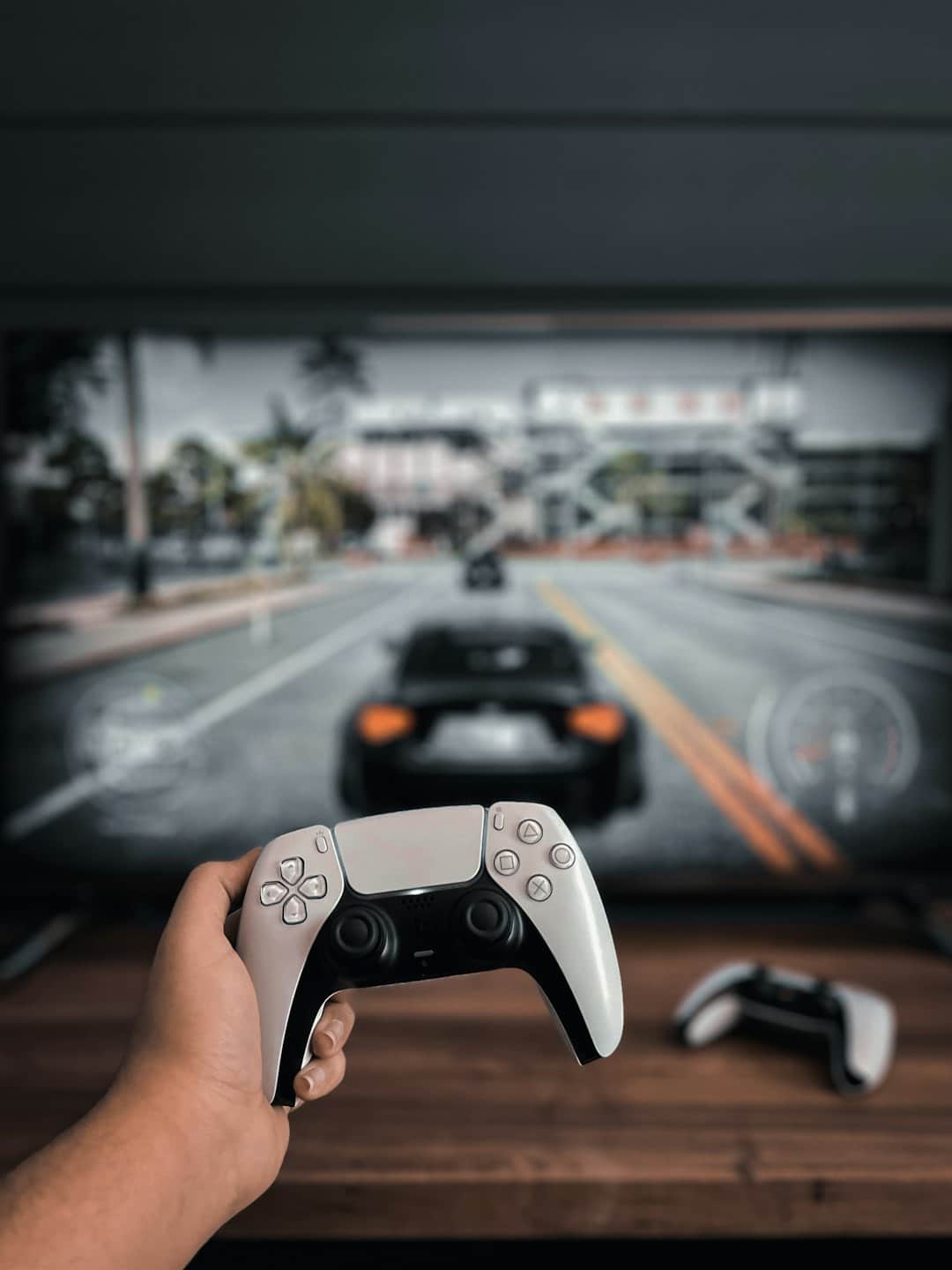 Mani che tengono un controller di gioco davanti a una televisione.